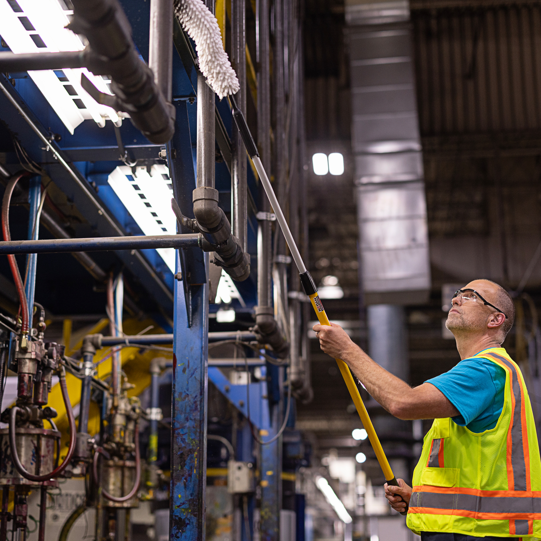 A warehouse aisle between racking, with a ride-on scrubber's cleaned track running down the centre.